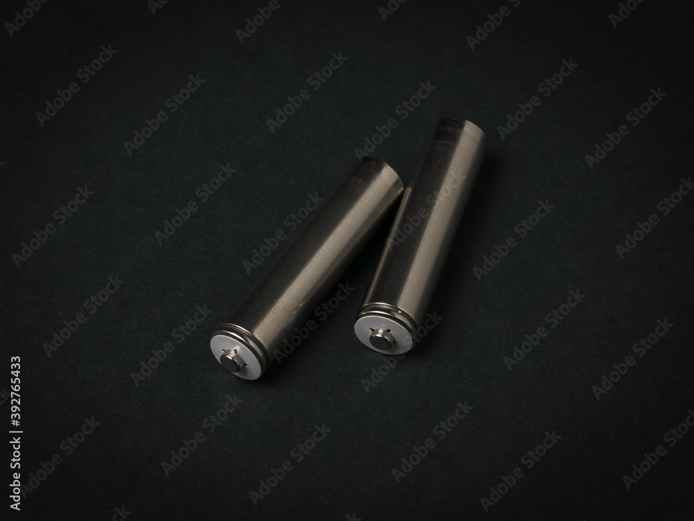 Two gray AA batteries on a black background.