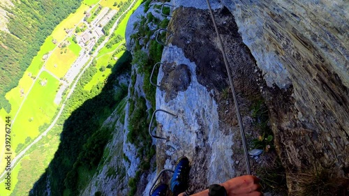 A man taking slow steps across metal steps at an altitude of 800m. Underneath him is the valley of lauterbrunnen in Switzerland. You see it all through his eyes. photo