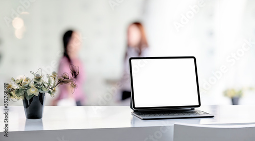 Mockup blank screen tablet and keyboard on wooden white top table in modern office room.
