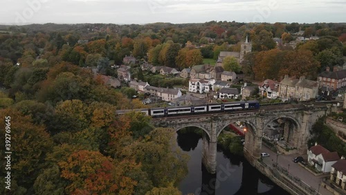 Drone shot above Knaresborough viaduct while train passes on it, in a beautiful autumn day. photo