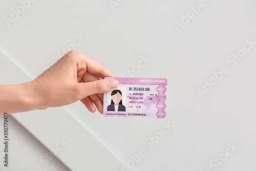 Female hand with driving license on light background photo