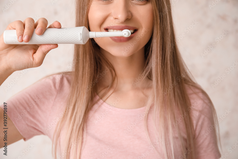 Young woman with electric tooth brush on light background Young woman with electric tooth brush on light background