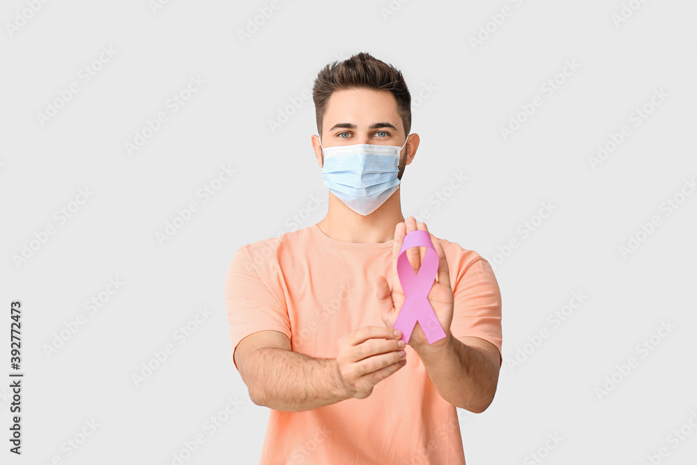 Man with pink ribbon on light background. Breast cancer awareness concept