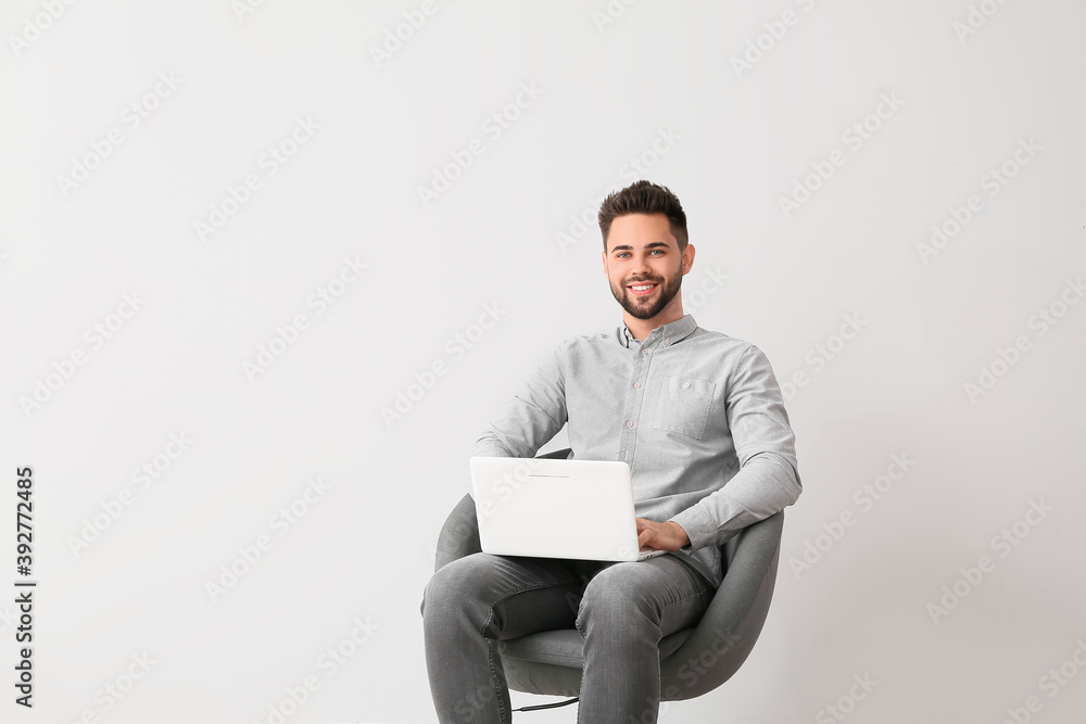 Male psychologist with laptop sitting in armchair on light background Male psychologist with laptop sitting in armchair on light background