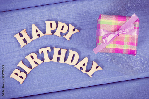 Wrapped gift with ribbon for birthday. Inscription happy birthday on boards