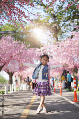 Asian little girl in garden under the blossom sakura tree background
