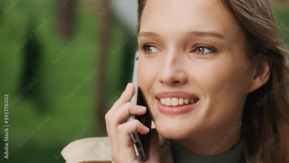 Close up shot of attractive smiling student girl having conversation on phone outdoor Close up shot of attractive smiling student girl having conversation on phone outdoor