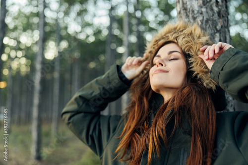Woman jackets outdoors near a tree with closed eyes in the forest
