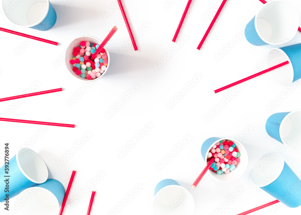 The concept of preparing for a party, event, celebration. Blue paper cups, red straws and colorful balls are on a white background. Template for christmas, new year, invitation, banner. Flat lay. The concept of preparing for a party, event, celebration. Blue paper cups, red straws and colorful balls are on a white background. Template for christmas, new year, invitation, banner. Flat lay.