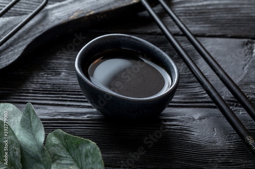 soy sauce in a ceramic saucepan. Black wooden background and decor.