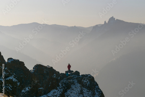 Panorama of mountains in winter. People on the rocky ridge. White snow and fog. Concept of winter tourism in the mountains.