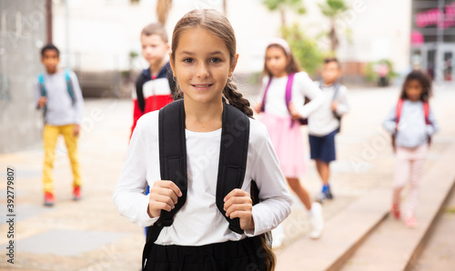 Portrait of smiling tween schoolgirl with backpack on her way to school on autumn day. Back to school concept.
