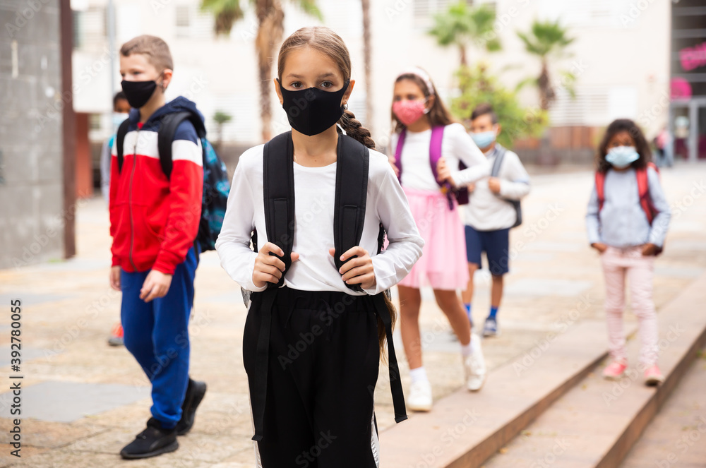 Portrait of tweenager girl in protective mask with backpack going to school lessons on warm autumn day. New lifestyle during coronavirus pandemic.