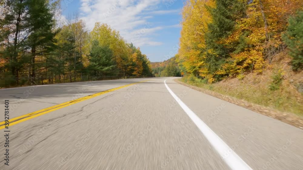 POV Driving a car on asphalt mountain road with colorful trees in fall. Sunny day with blue sky and white clouds POV Driving a car on asphalt mountain road with colorful trees in fall. Sunny day with blue sky and white clouds