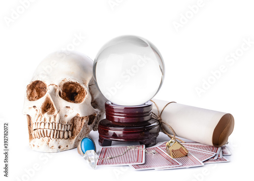 Crystal ball of fortune teller, human skull, cards and scroll on white background