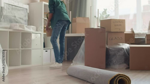 Lockdown of young African-American man taking indoor plant and carrying it away then taking rolled carpet and carrying it out of room too