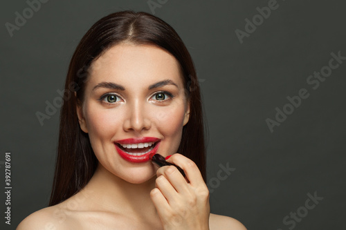 Fashion beauty portrait of pretty model woman face with red glossy lips and lipstick on black background
