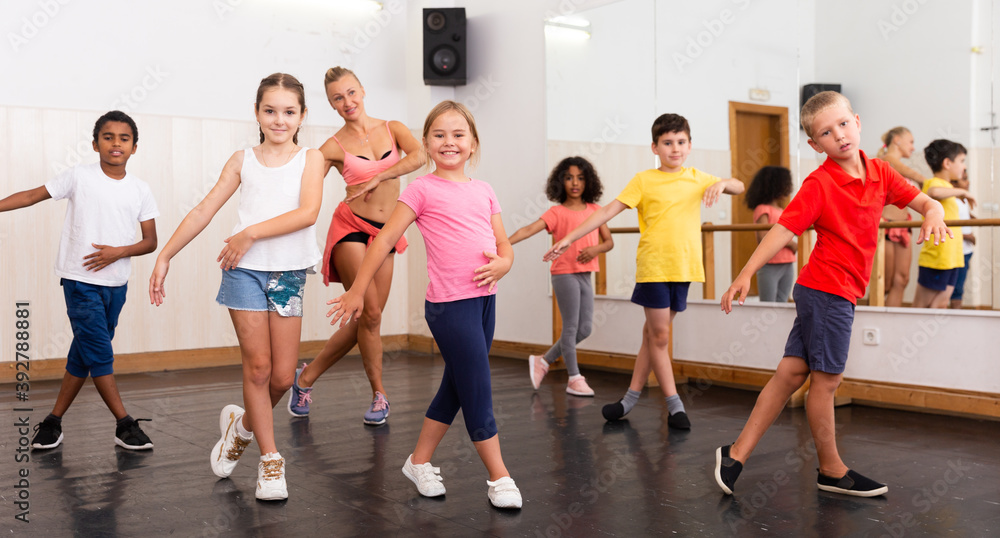 Group of children participating in dance class, following their teacher in dance school