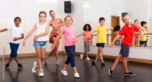 Fototapeta Naklejka Na Ścianę i Meble -  Group of children participating in dance class, following their teacher in dance school