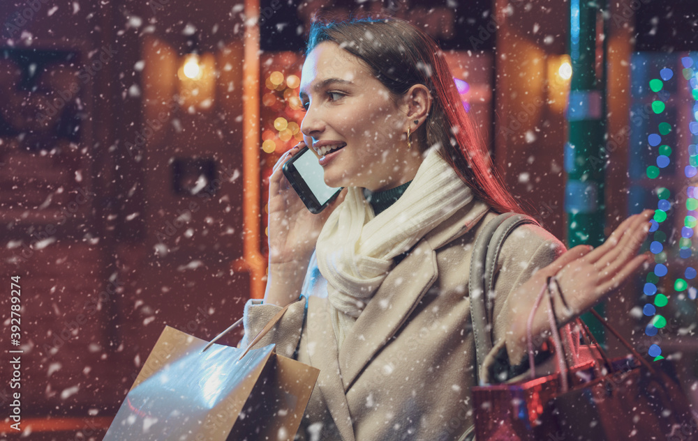 Happy woman doing Christmas shopping and talking on the phone Happy woman doing Christmas shopping and talking on the phone