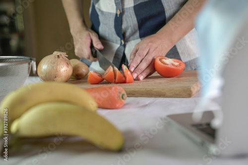 Woman cutting tomatoes on chopping board, preparing meal.