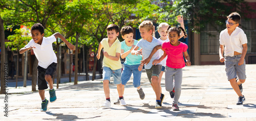 Group of happy kids running in race in the street and laughing outdoors