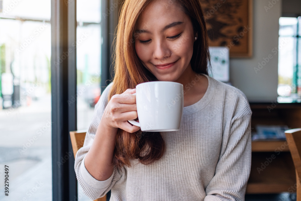 Closeup image of a beautiful young asian woman holding and drinking coffee in cafe Closeup image of a beautiful young asian woman holding and drinking coffee in cafe