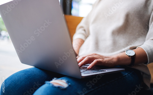 Closeup image of a businesswoman working and typing on laptop computer keyboard on the table