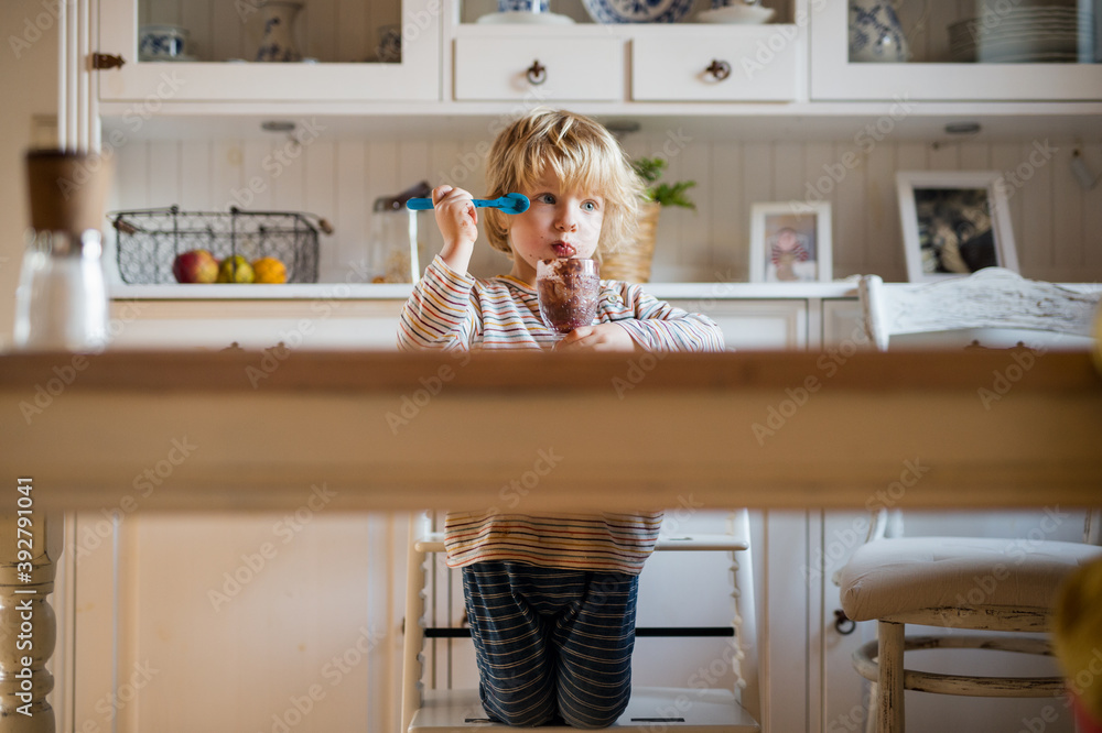 Small boy with dirty mouth indoors in kitchen at home, eating pudding. Small boy with dirty mouth indoors in kitchen at home, eating pudding.