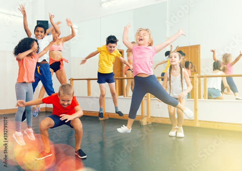 Fototapeta Naklejka Na Ścianę i Meble -  Happy kids of different nationalities and ages jumping during class in dance school