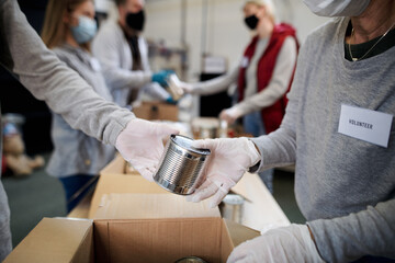 Group of volunteers in community donation center, food bank and coronavirus concept.