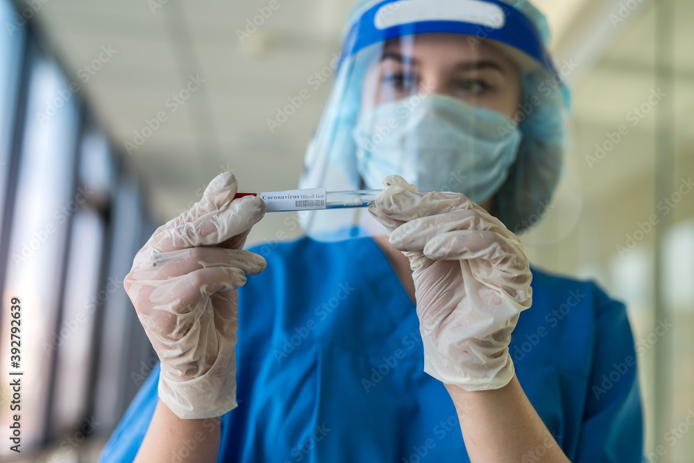 young nurse in protective suit and face shield holding a positive blood test result for covid-19 young nurse in protective suit and face shield holding a positive blood test result for covid-19