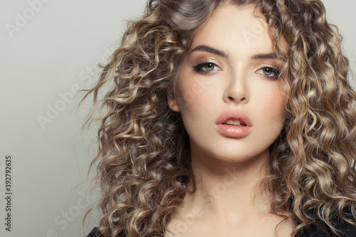 Attractive young model woman with curly hair on white, fashion beauty portrait