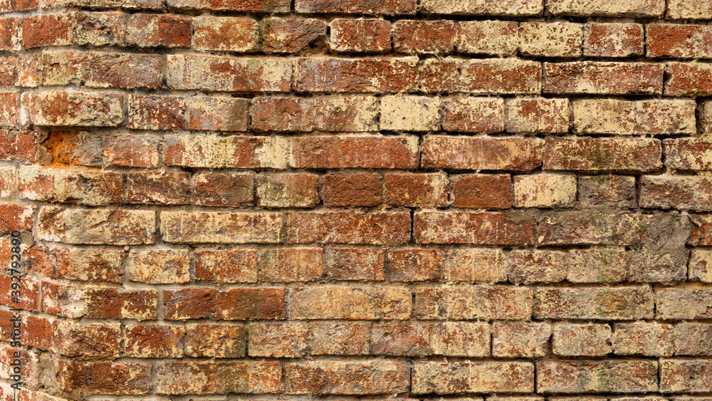 Obraz premium The exterior wall of the building is made of red brick with damage, traces of cement, white lime coating