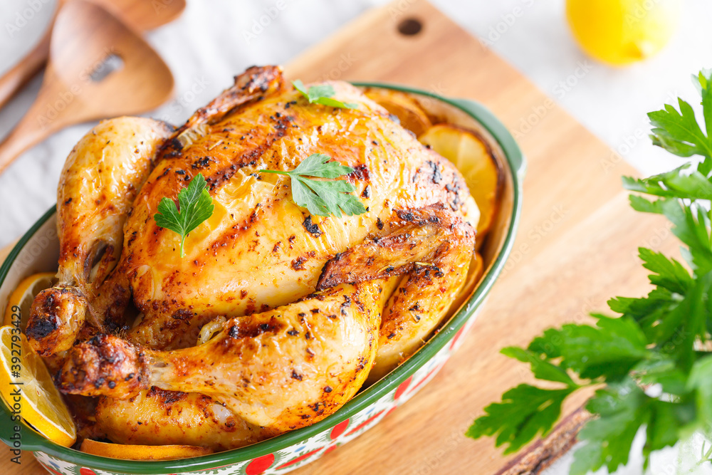 Whole roasted chicken with fresh parsley and lemon wedges in a festive dish