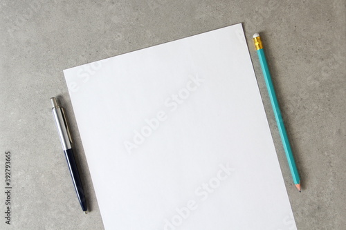 Template of white paper with a ballpoint pen and simple pencil on light grey concrete background. Concept of new idea, business plan and strategy,  empty space for text