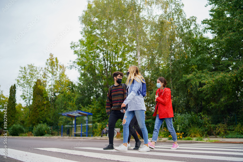 Group of young people crossing road outdoors in town, talking. Coronavirus concept. Group of young people crossing road outdoors in town, talking. Coronavirus concept.