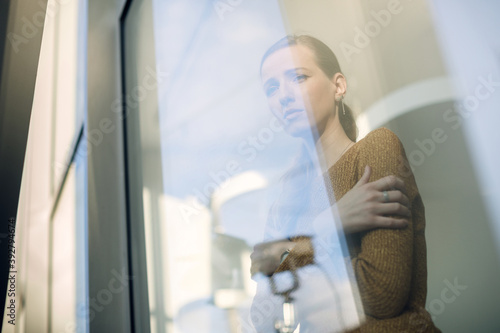 Below view of depressed woman looking through the window.
