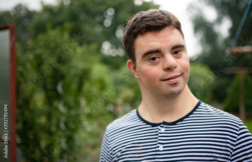 Portrait of down syndrome adult man standing outdoors in garden.