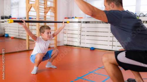 Foto Squats with a bar, strength training and exercise for children