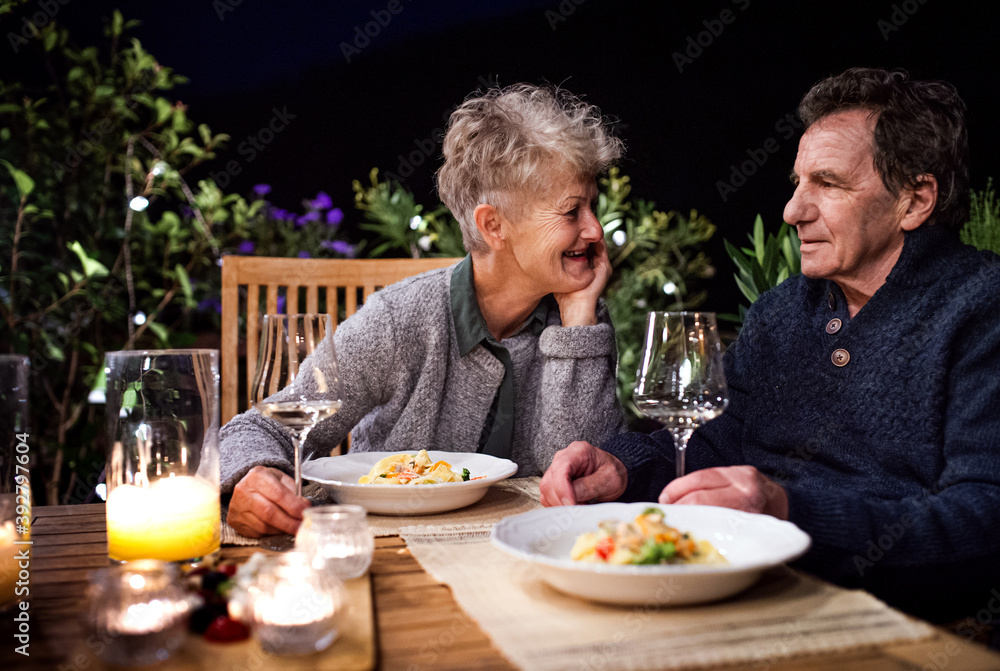 Senior couple having dinner in the evening on terrace, drinking wine. Senior couple having dinner in the evening on terrace, drinking wine.