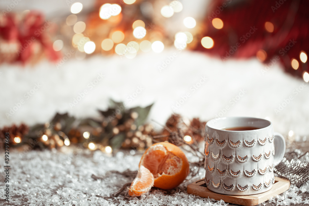 Cozy winter background with a beautiful cup and tangerine on a blurred background with bokeh. Cozy winter background with a beautiful cup and tangerine on a blurred background with bokeh.