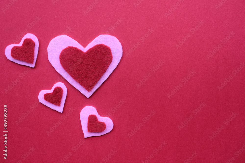 Handmade hearts made of felt fabric on red background. Flat lay valentine`s day composition. Copy space