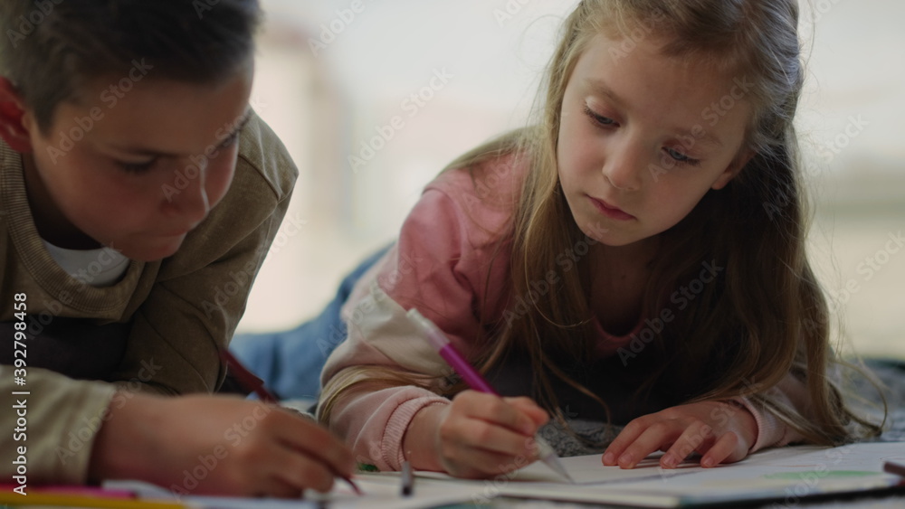 Children painting with colored pencils at home. Siblings drawing on sketchbooks. Children painting with colored pencils at home. Siblings drawing on sketchbooks.