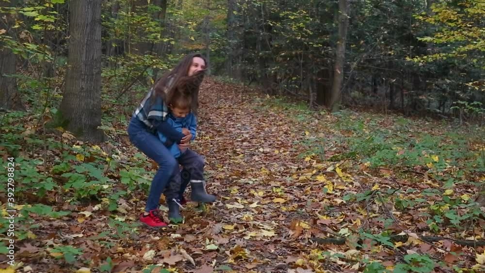 Mother catches her son in arms laughing, funny cuddles, playing in autumn forest Mother catches her son in arms laughing, funny cuddles, playing in autumn forest