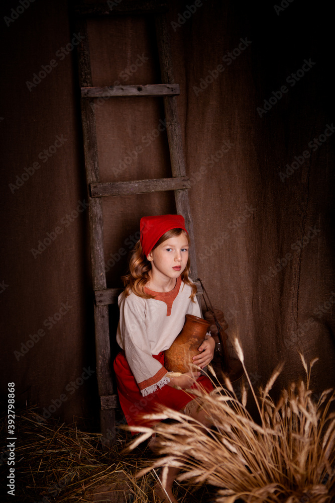 Obraz premium little girl in a light linen shirt and a red scarf in a rustic style