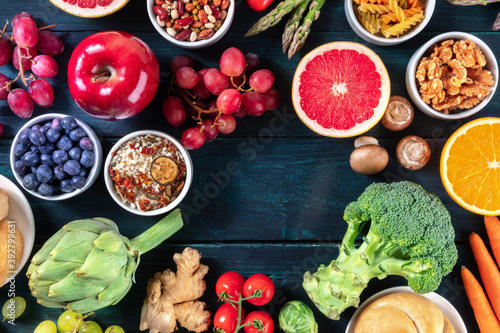 Vegan food background, a flatlay with fruit and vegetables, shot from the above with copy space on a dark blue wooden background