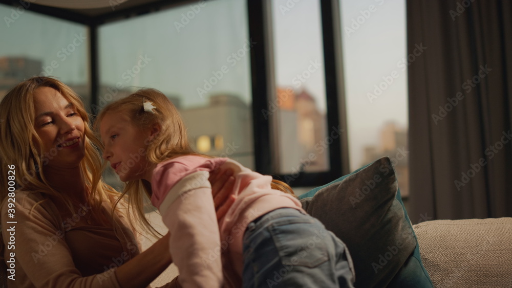 Mother hugging daughter on sofa at home. Mom and child spending time together. Mother hugging daughter on sofa at home. Mom and child spending time together.