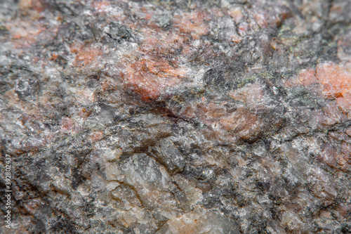 Photograph of a granite surface in soft focus at high magnification. Fine texture of natural mineral of pink color with blurred background. Stone with soft stains of color.