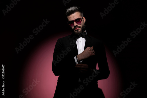 young businessman fixing his sleeve and wearing sunglasses